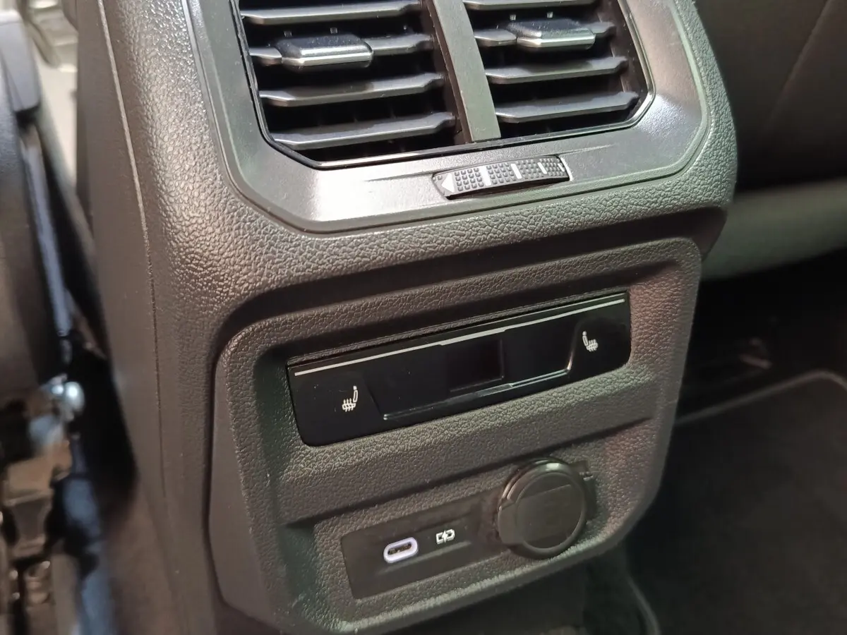 Détail intérieur du Volkswagen Tiguan blanc 2023 montrant la ventilation arrière et les commandes de sièges chauffants.