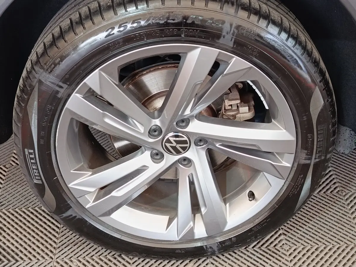 Gros plan sur la jante alliage argentée avec logo Volkswagen du Volkswagen Tiguan blanc 1.4 EHYBRID 2023.