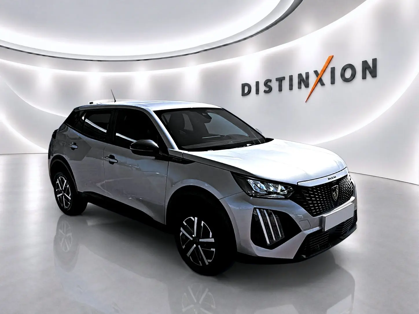 Peugeot 2008 gris en 3/4 avant droit, avec calandre noire et phares LED, dans un showroom lumineux.