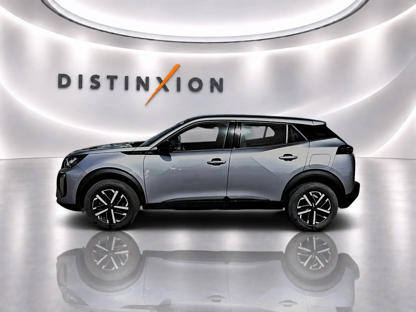 Profil côté gauche d’un Peugeot 2008 gris 2025 avec toit noir et jantes noires à motifs argentés, sur fond blanc lumineux.