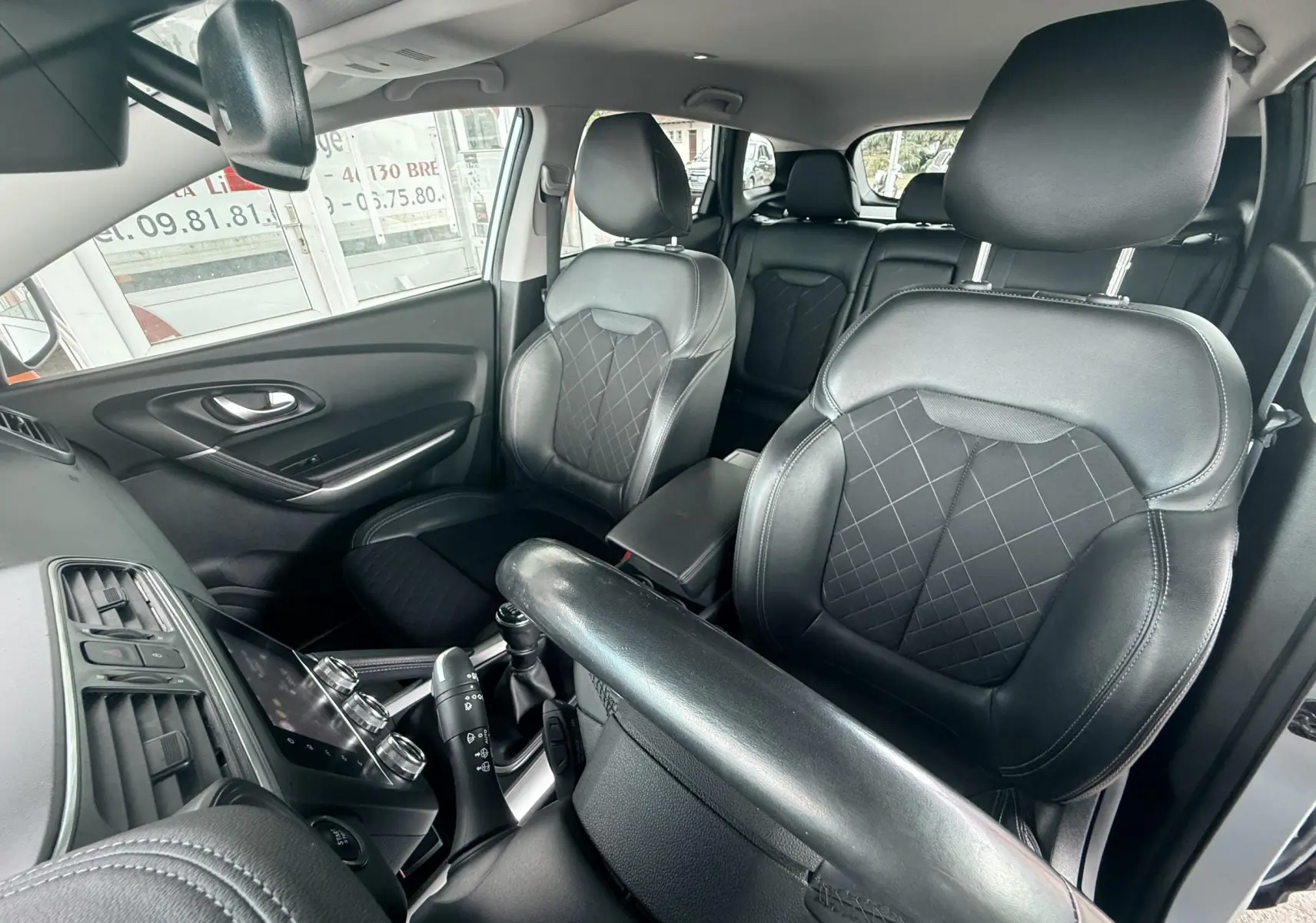 Vue intérieure du Renault Kadjar 2020 montrant les sièges avant en cuir noir avec surpiqûres et console centrale.