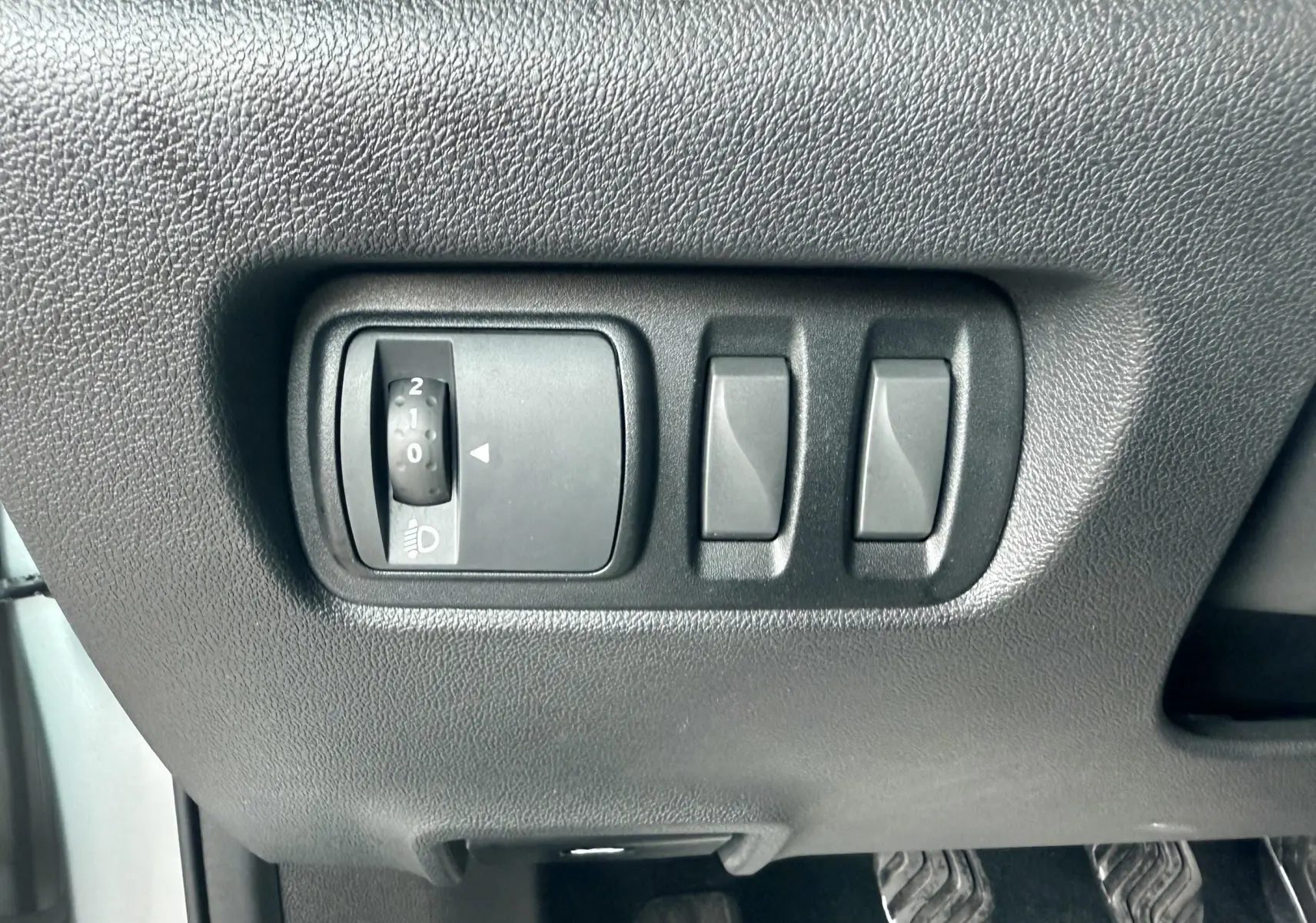 Gros plan sur les commandes de réglage des phares et des rétroviseurs côté conducteur du Renault Kadjar gris.