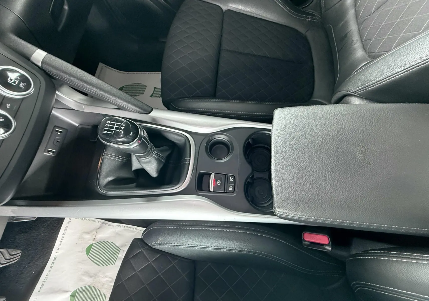 Vue plongeante sur la console centrale du Renault Kadjar gris, montrant la boîte manuelle et les sièges en cuir noir matelassé.