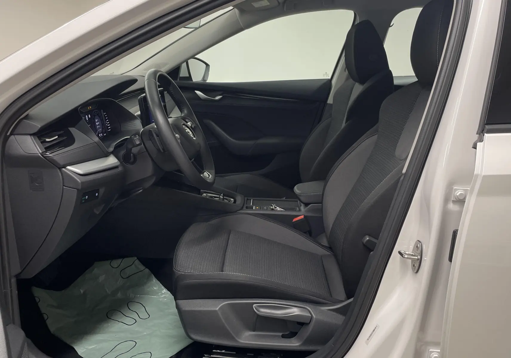 Intérieur côté conducteur d'une Skoda Octavia 2024 blanc candy, sièges noirs et tableau de bord moderne.