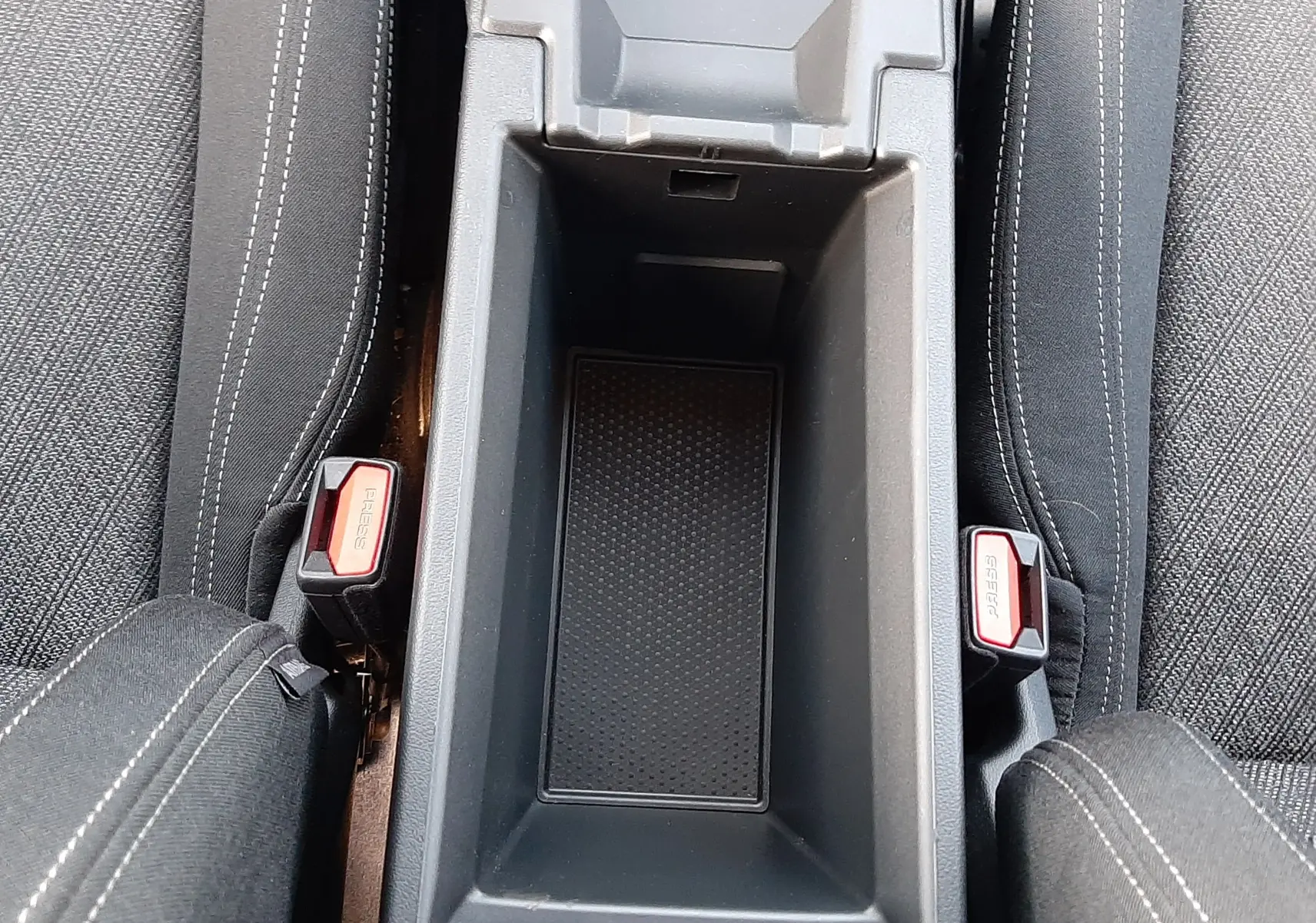 Vue plongeante sur le rangement central entre les sièges en tissu noir de la BMW Série 1 F70 120D M Sport Design