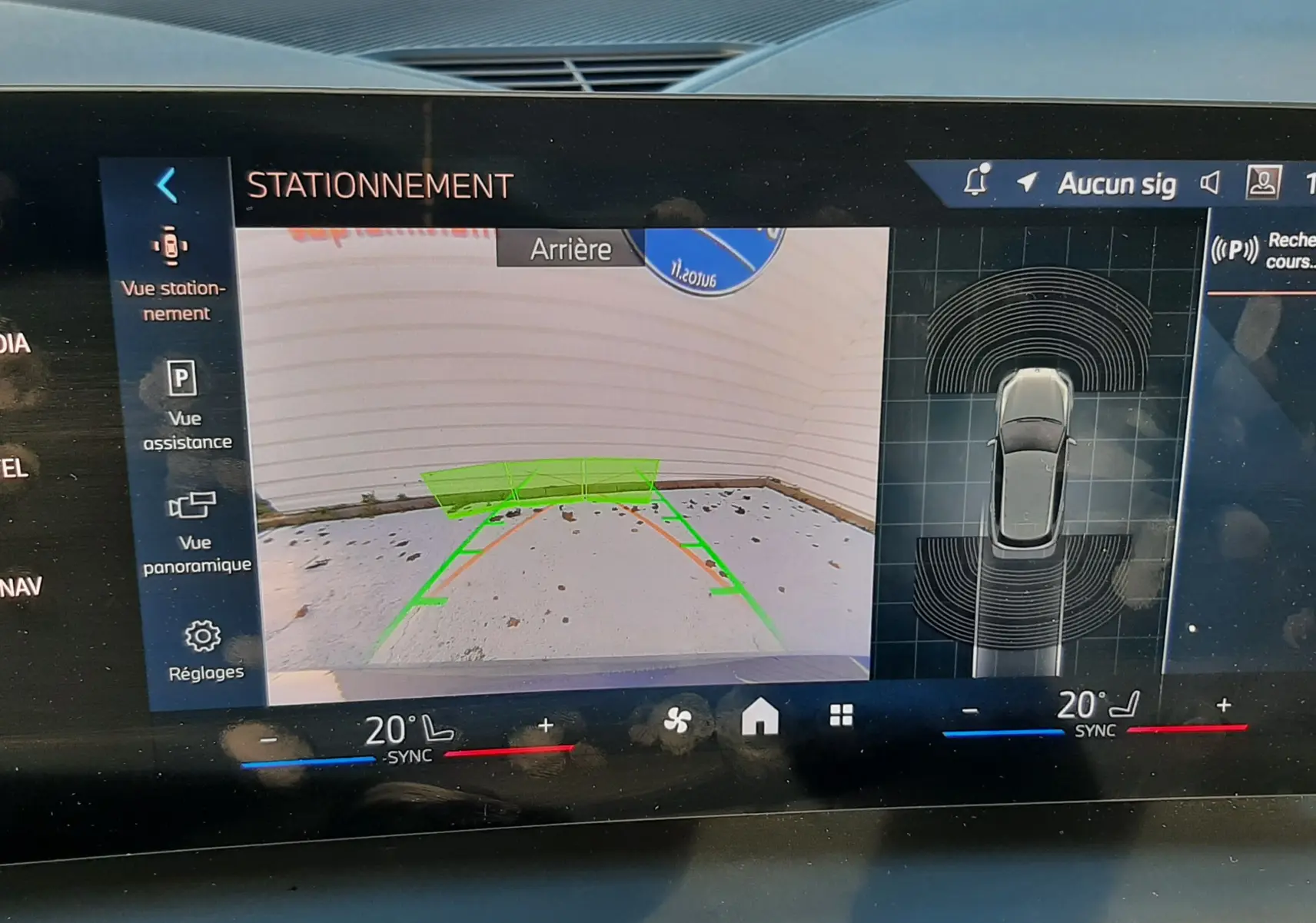 Écran de la BMW Série 1 120D M Sport 2025 montrant l'assistance au stationnement avec vue arrière et capteurs actifs.