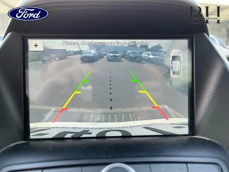 Écran de caméra de recul du Ford Kuga blanc Glacier montrant l'arrière avec lignes de guidage colorées.