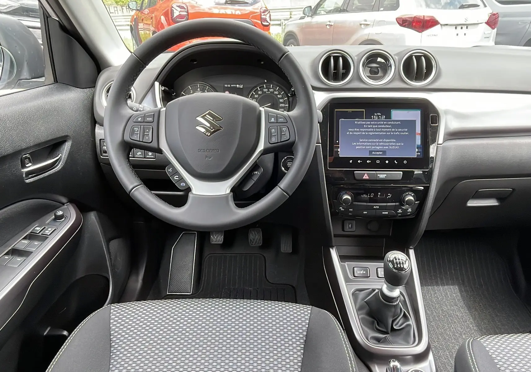 Vue intérieure frontale du Suzuki Vitara 2025 montrant le volant multifonctions, écran tactile 9 pouces et levier de vitesse manuel.