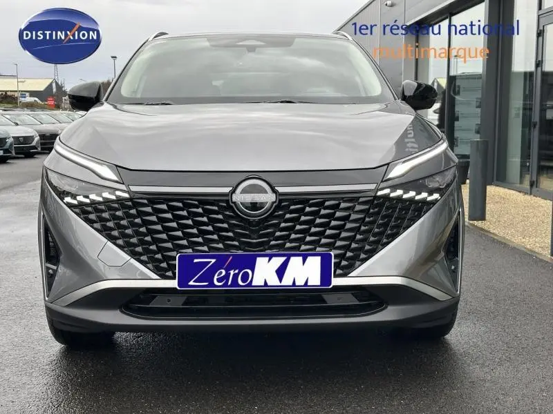 Vue frontale du Nissan Qashqai Hybrid e-POWER 2025 en gris squale métallisé avec calandre noire texturée et feux LED distinctifs.