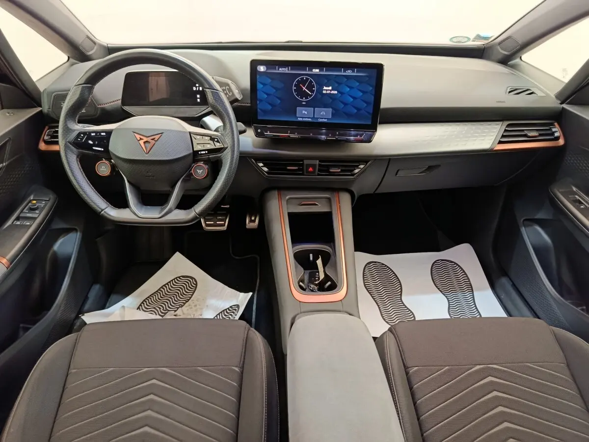 Intérieur du CUPRA BORN 230ch 2023 vu de face, volant cuir, écran tactile central et finitions cuivre.