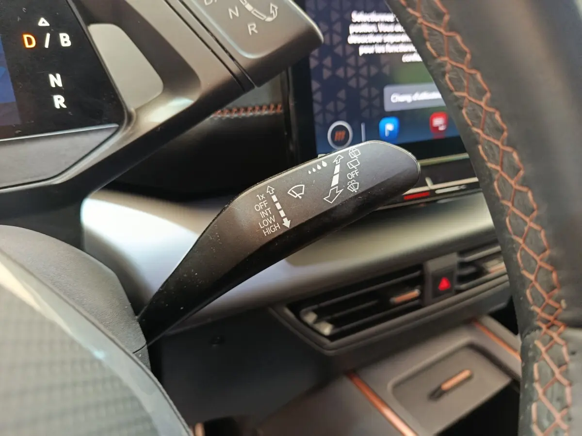 Gros plan sur la commande des essuie-glaces dans l’habitacle du CUPRA Born 230ch, volant cuir avec surpiqûres orange visible.