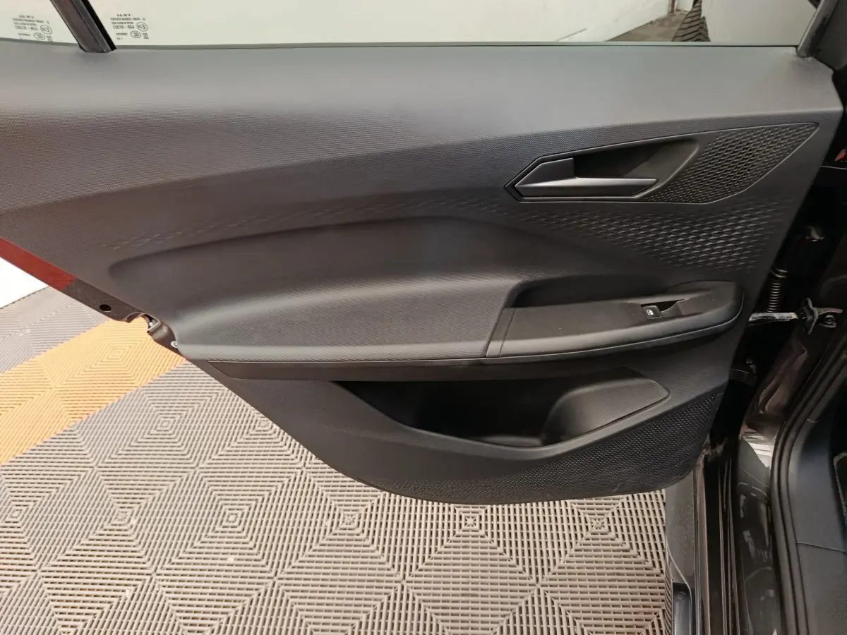 Vue latérale du panneau de porte avant droit gris foncé du CUPRA BORN 230ch avec poignée et commande de vitre électrique.