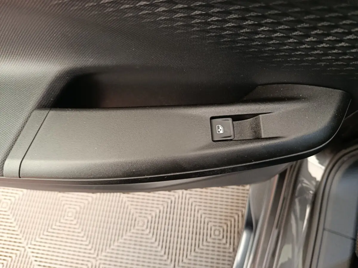 Détail de la commande de lève-vitre électrique sur la porte côté conducteur d'une CUPRA Born gris foncé.