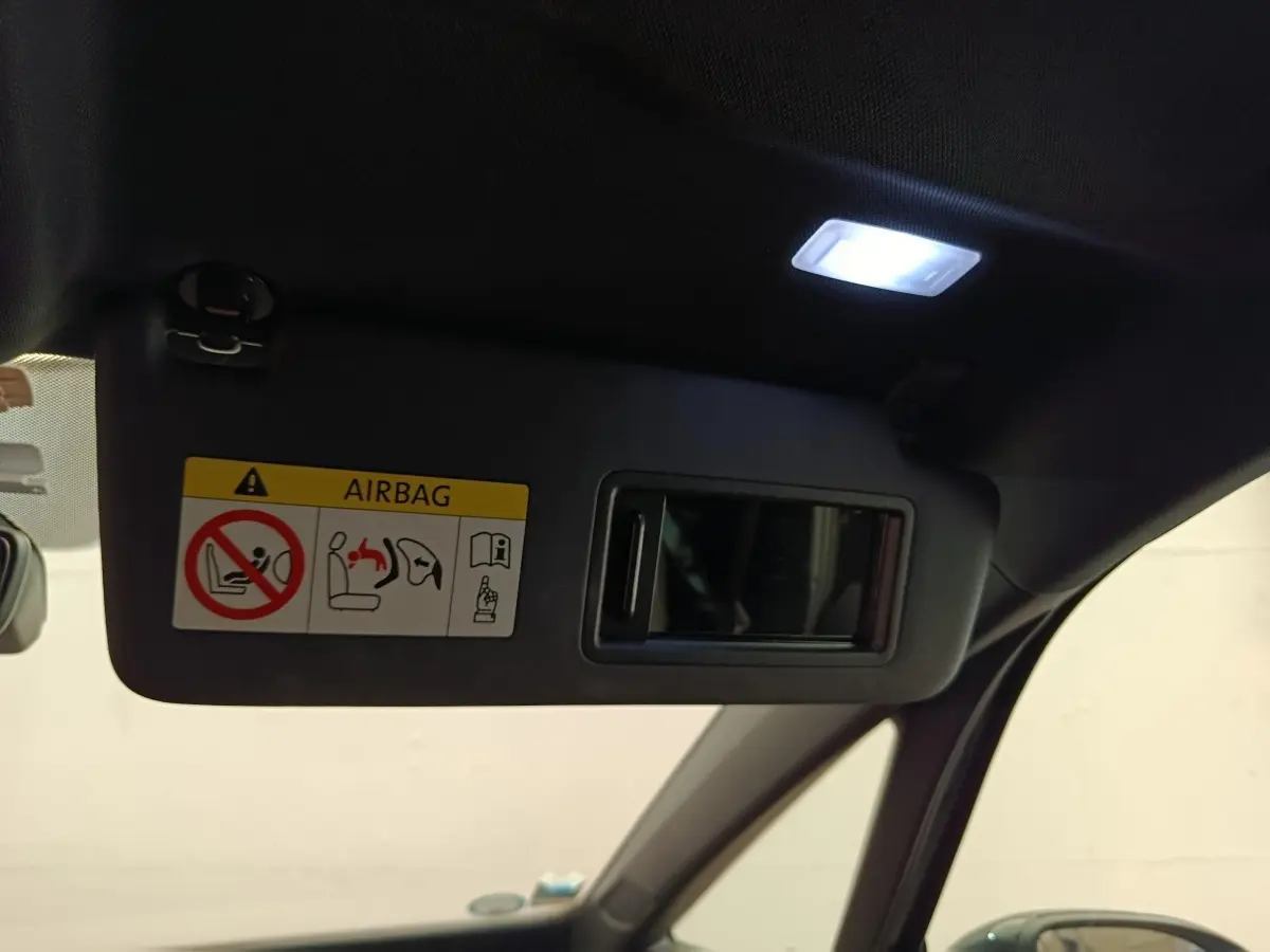 Détail du pare-soleil côté conducteur avec miroir intégré et éclairage intérieur allumé dans un CUPRA Born gris foncé.