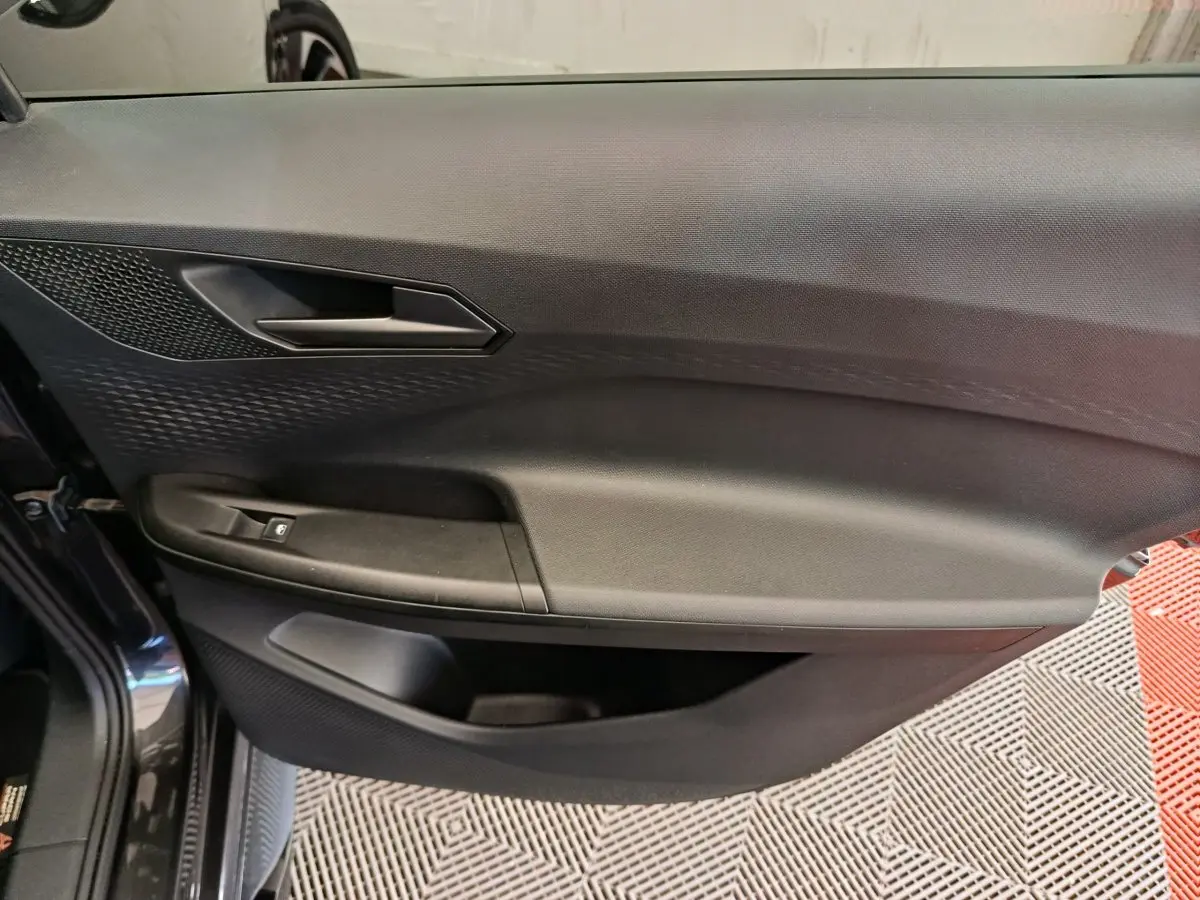 Gros plan sur la porte intérieure côté gauche d'une CUPRA BORN gris foncé, avec poignée et commande de vitre visible.