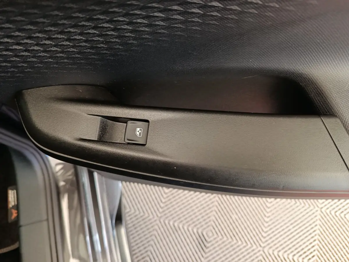 Détail de la commande de lève-vitre électrique sur la porte intérieure côté conducteur d’une CUPRA Born gris foncé.