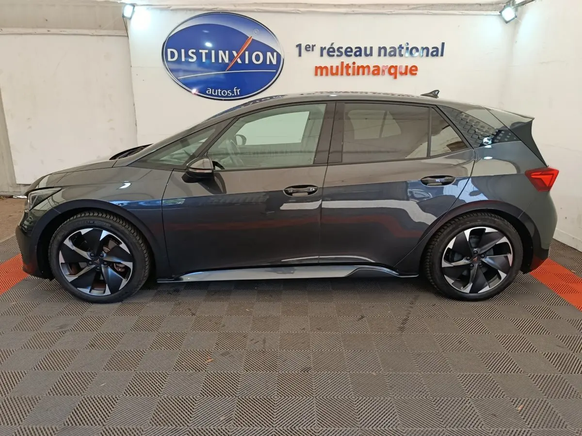 Vue de profil côté gauche d'une CUPRA BORN 230ch gris foncé avec jantes noires et toit noir brillant.
