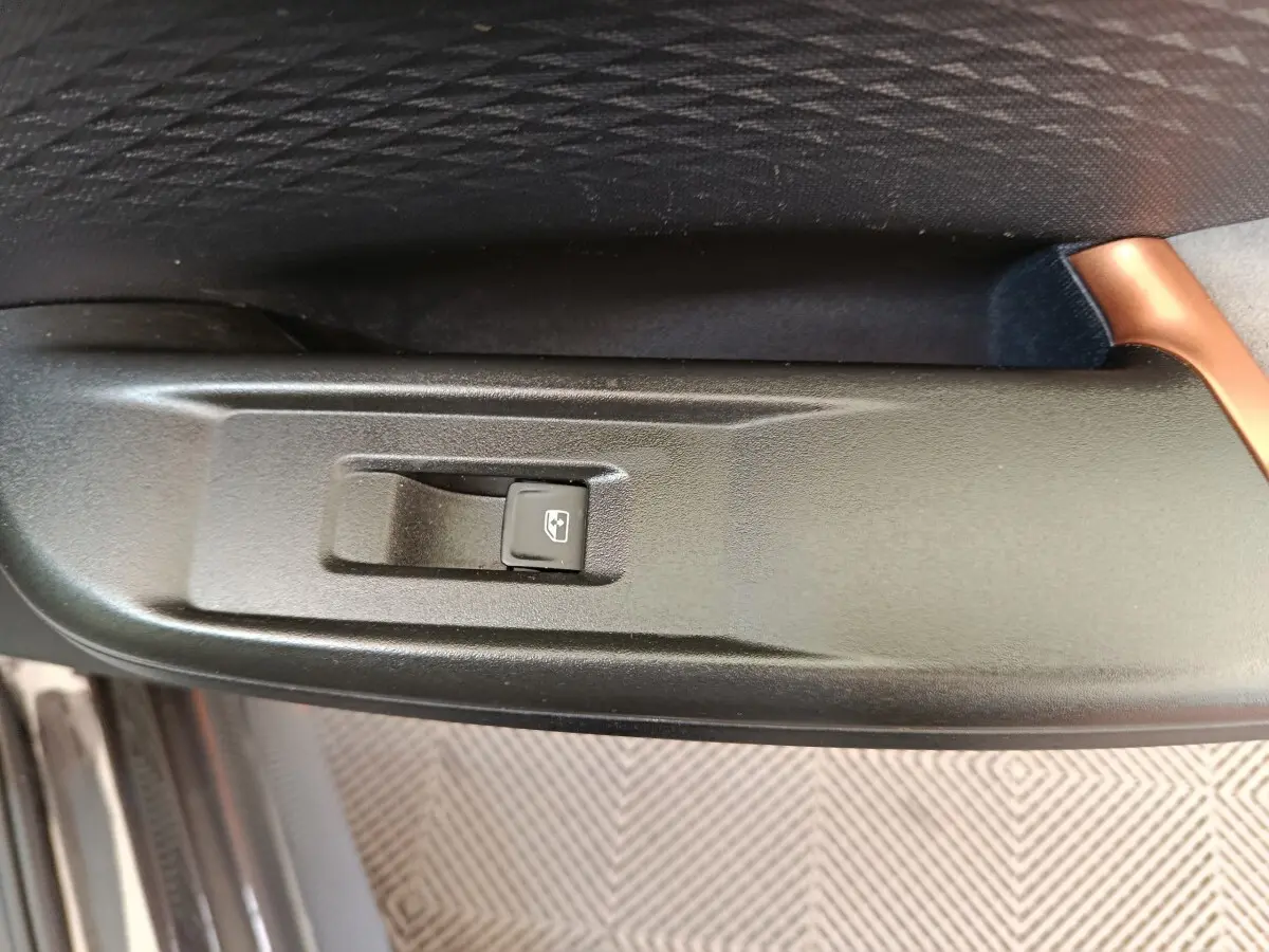 Gros plan sur l'interrupteur de lève-vitre électrique côté conducteur dans l'habitacle noir du CUPRA Born 2023.