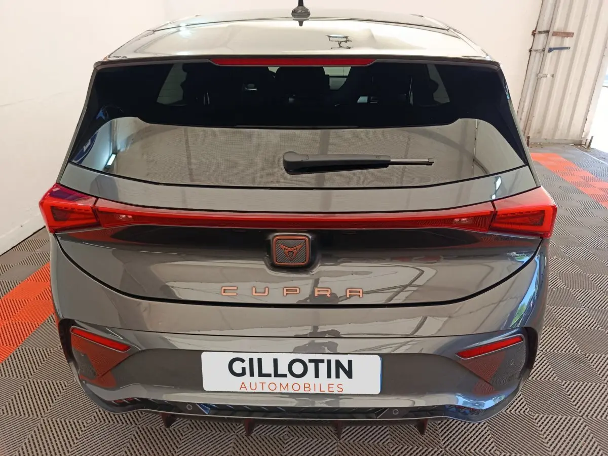 Vue arrière d'une CUPRA BORN gris foncé avec feux arrière LED reliés et logo CUPRA central lumineux.
