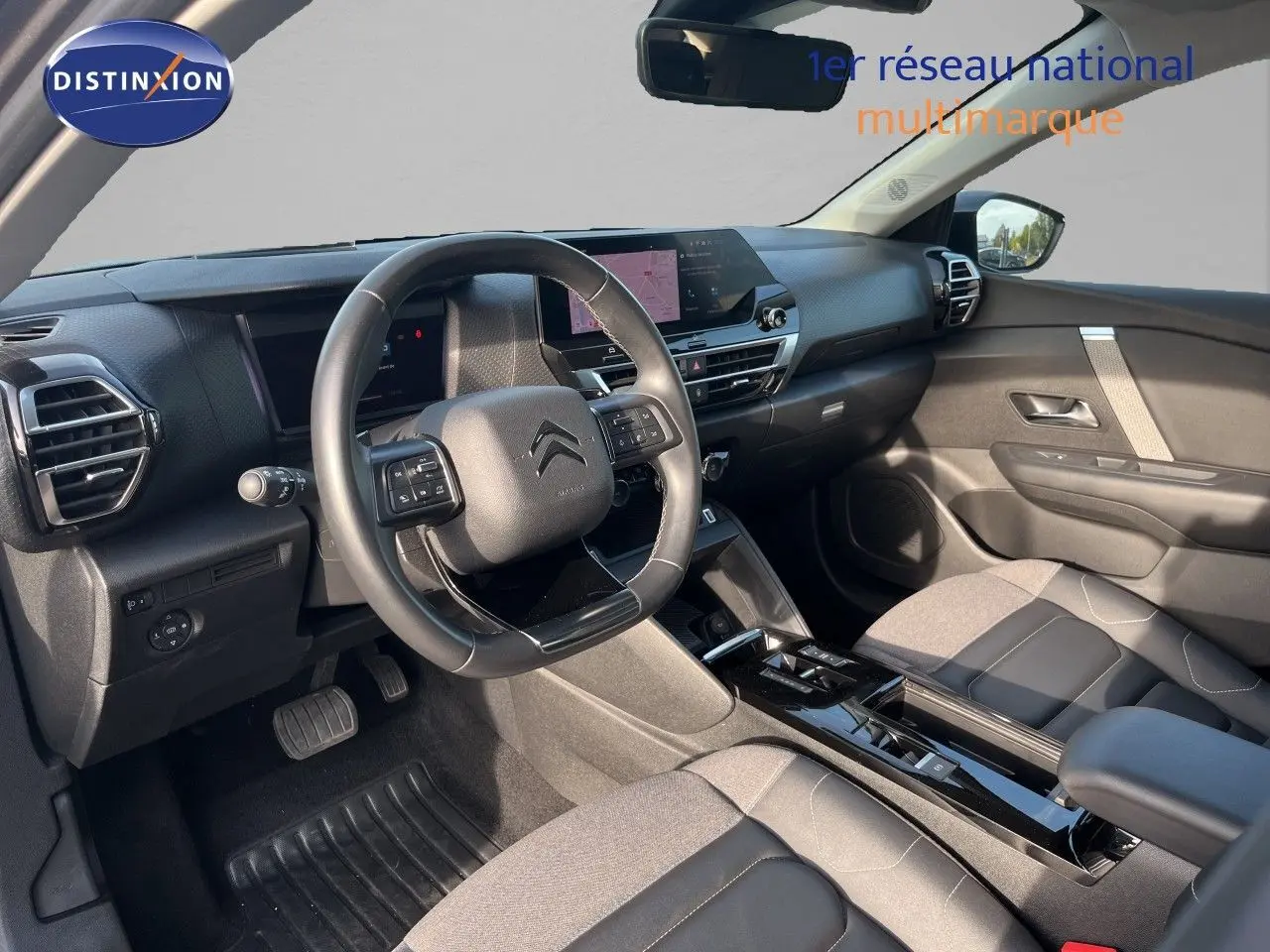 Intérieur de la Citroën C4 2023 en gris, vue côté conducteur montrant tableau de bord et volant multifonction.