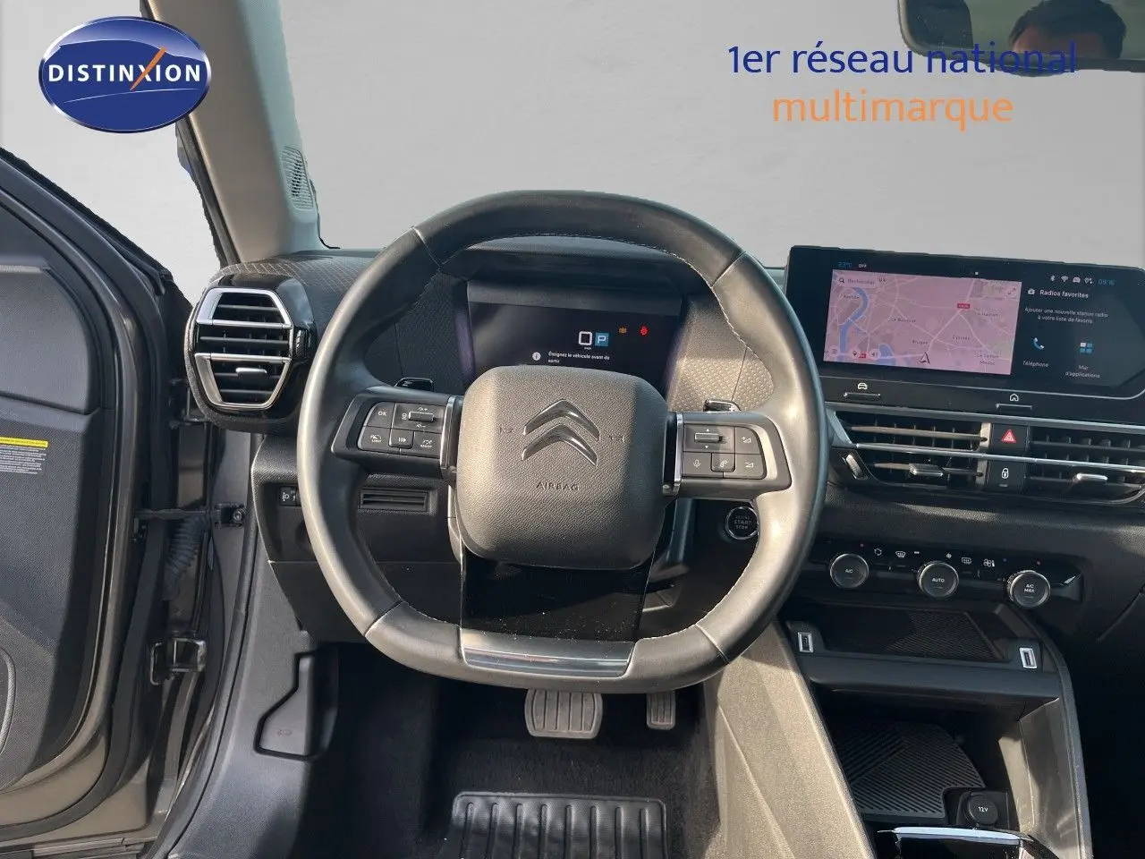 Vue intérieure centrée sur le volant noir d'une Citroën C4 2023 avec tableau de bord digital et écran tactile.