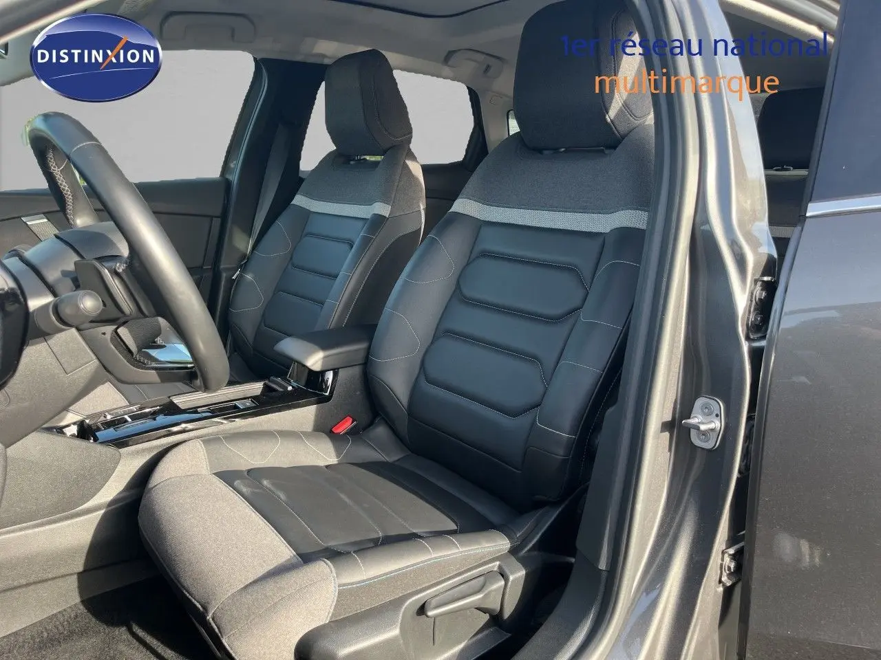 Vue intérieure côté conducteur de la Citroën C4 2023 gris, sièges en tissu et cuir noir avec détails gris.