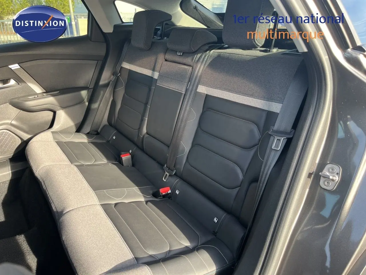 Vue intérieure de la banquette arrière bicolore gris et noir du Citroën C4 2023, avec ceinture et porte ouvert côté droit.