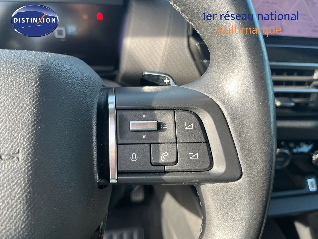 Gros plan sur les commandes au volant côté gauche du Citroën C4 gris 2023, avec boutons de volume et téléphone.