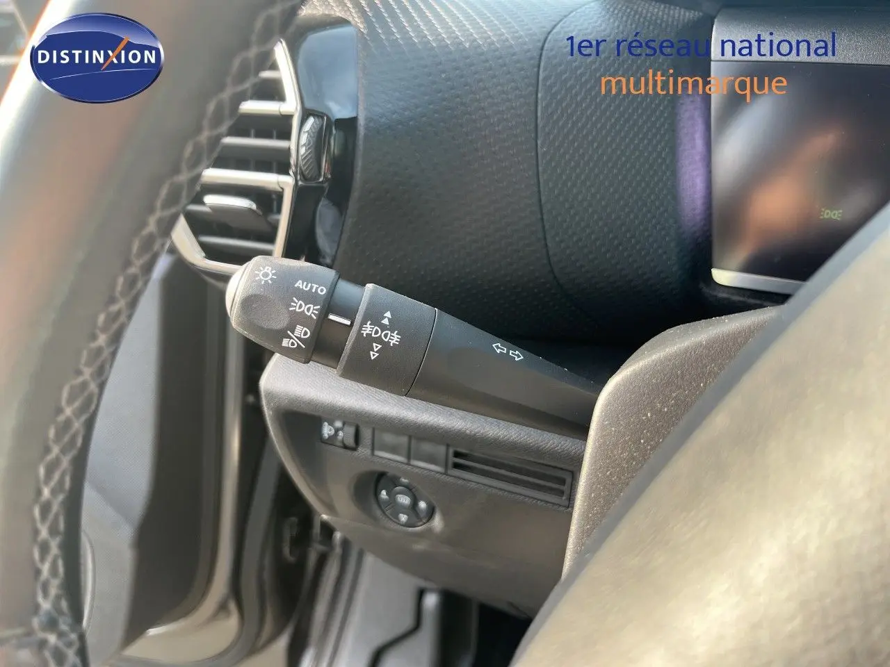 Vue intérieure côté conducteur du commodo d’éclairage et clignotants sur Citroën C4 gris 2023.