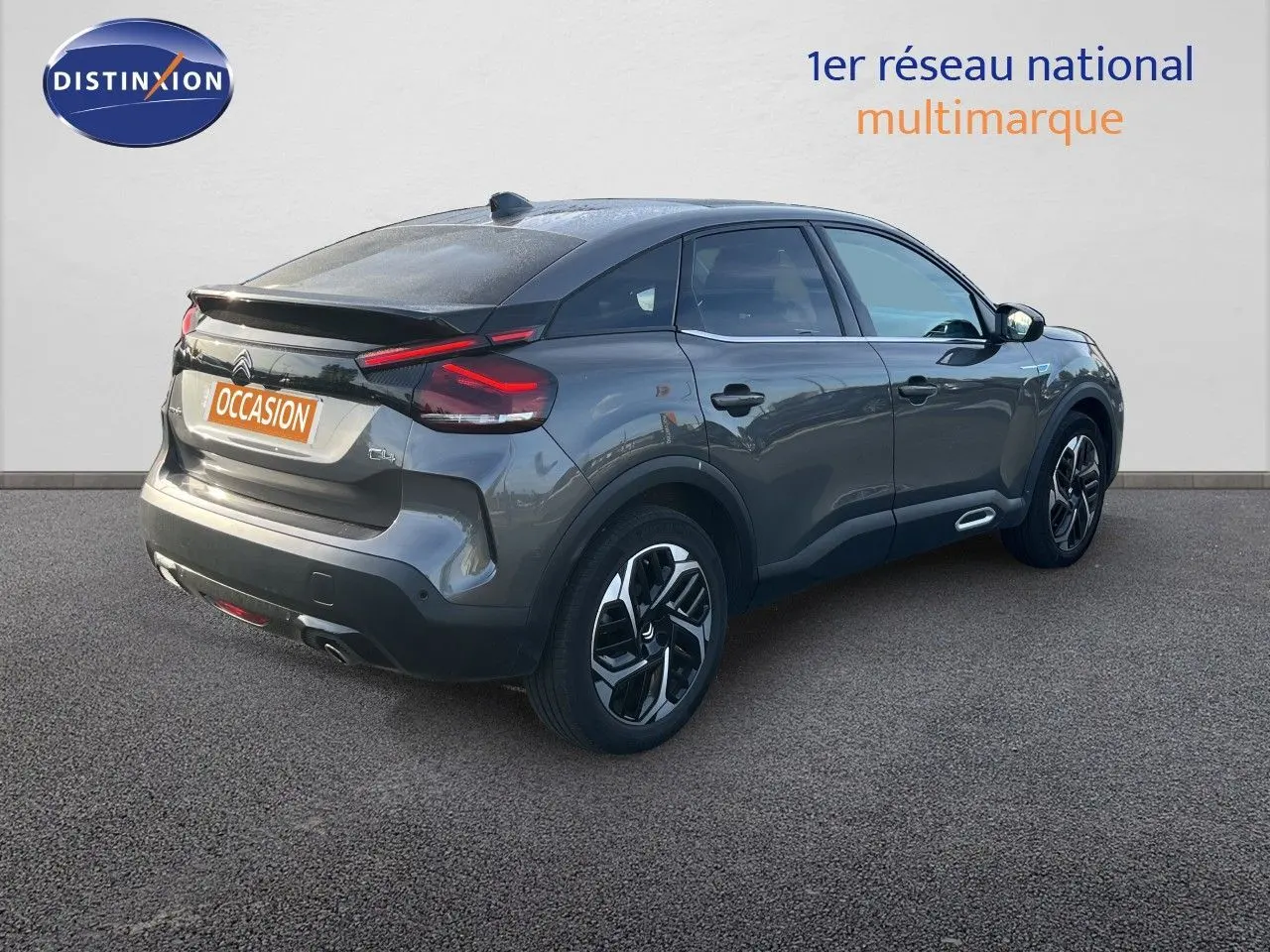 Vue 3/4 arrière droite d'une Citroën C4 gris métallisé 2023 avec feux arrière LED et jantes alliage noires.