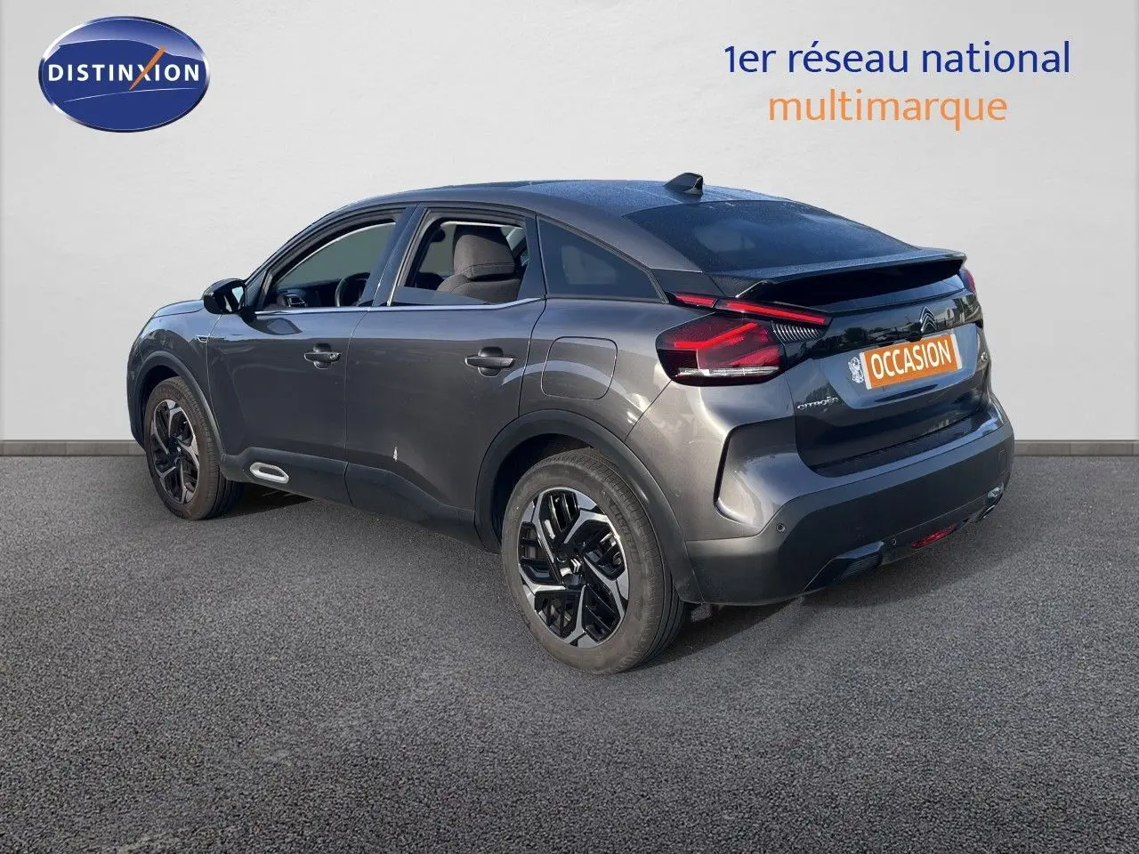 Citroën C4 gris en 3/4 arrière droit, mettant en valeur ses feux arrière LED et ses jantes noires bicolores.