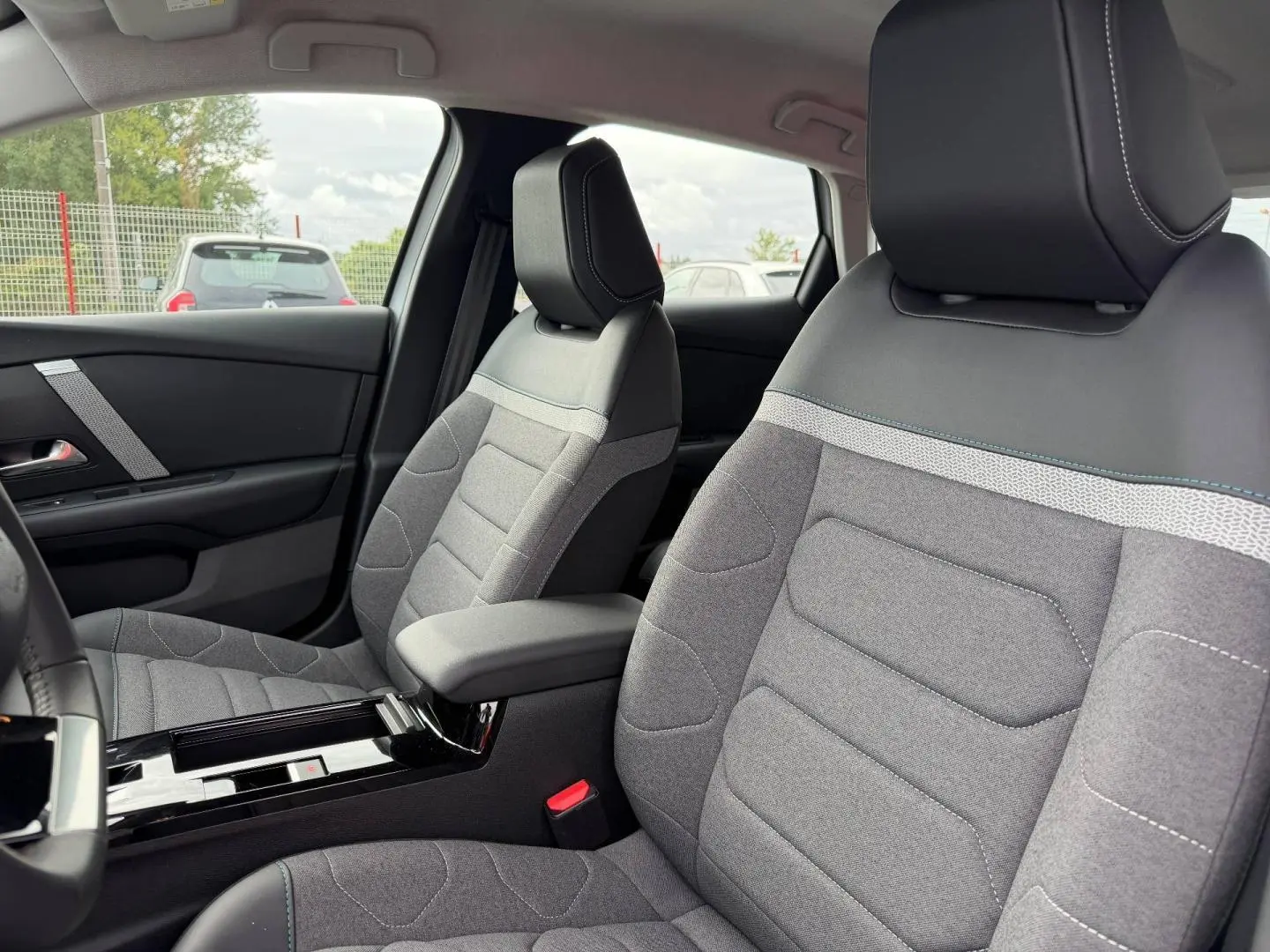 Vue intérieure des sièges avant gris et noir avec surpiqûres blanches de la Citroën C4 électrique 2024, côté conducteur.