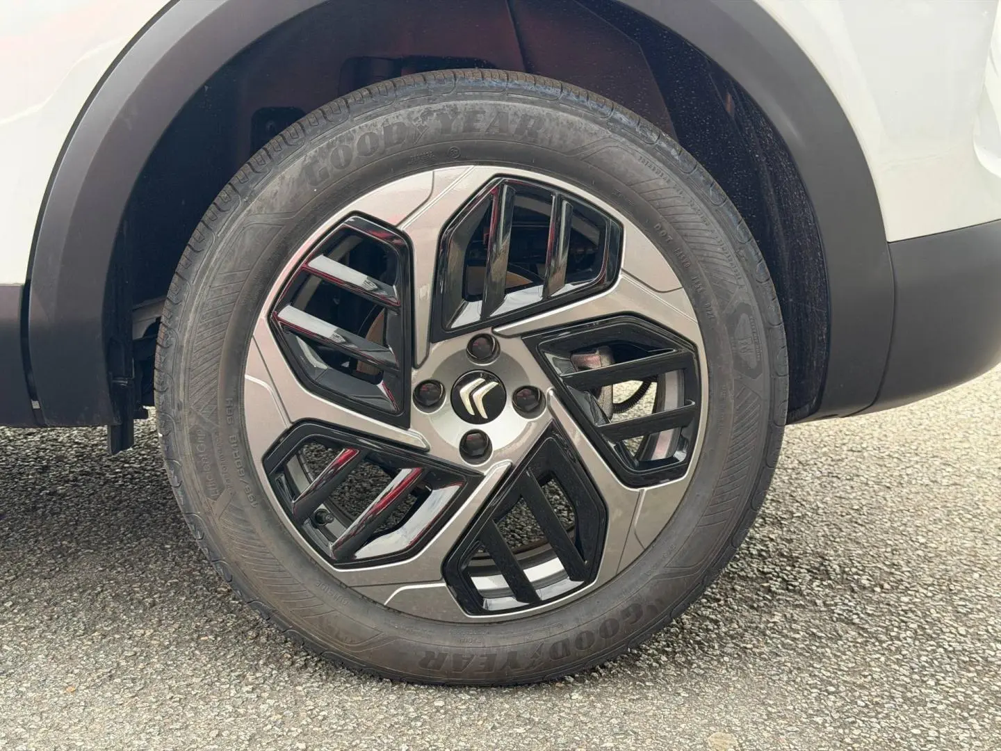 Gros plan sur la roue avant droite d'une Citroën C4 électrique blanche, avec jante alliage noire et argentée.