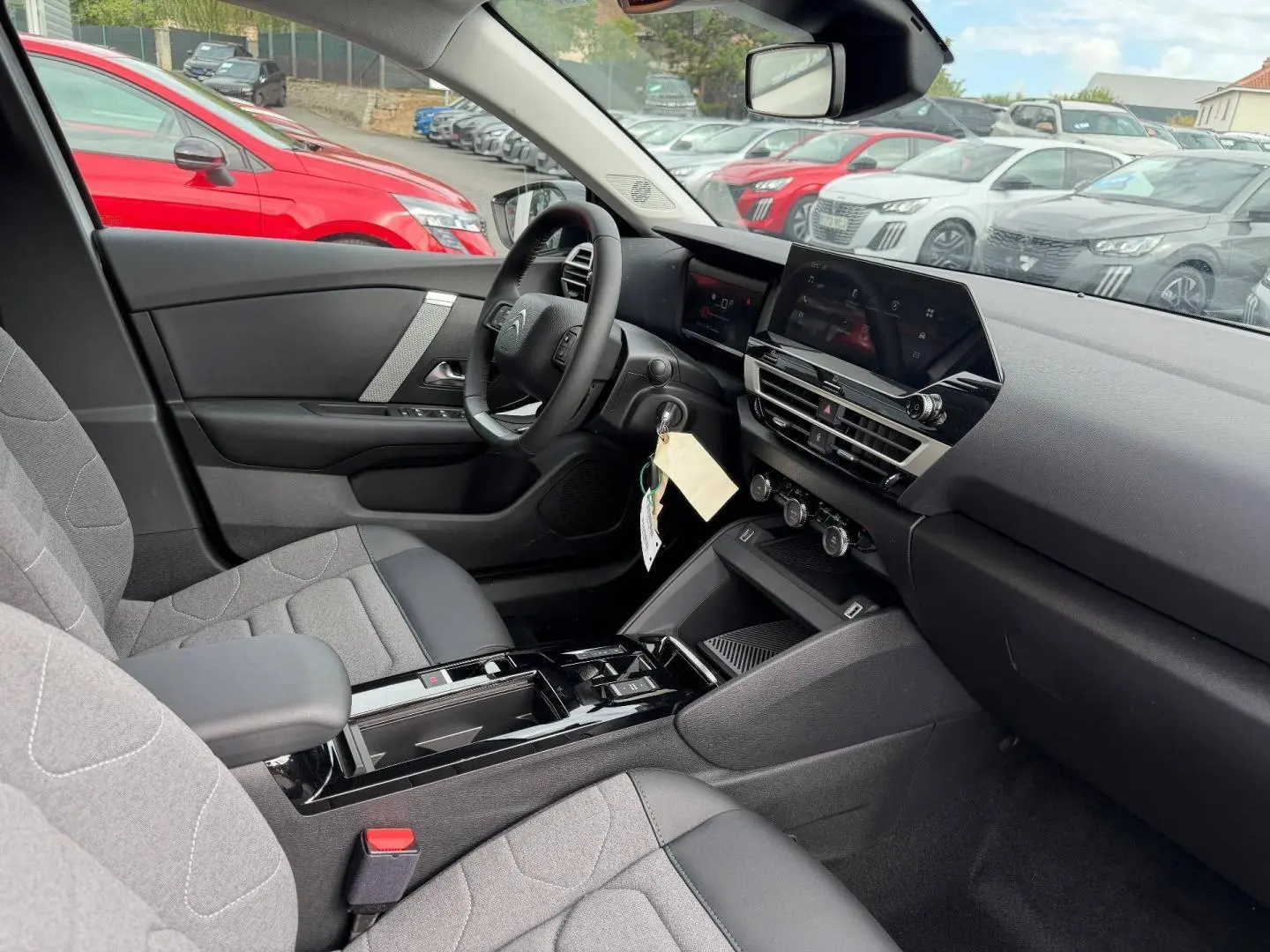 Vue intérieure côté conducteur du Citroën C4 2024 électrique, montrant sièges gris et tableau de bord moderne.