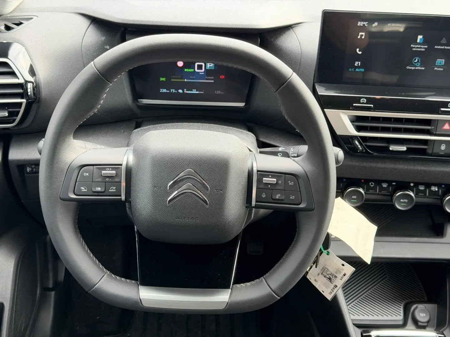 Vue rapprochée du volant noir et du tableau de bord numérique de la Citroën C4 électrique blanche 2024.