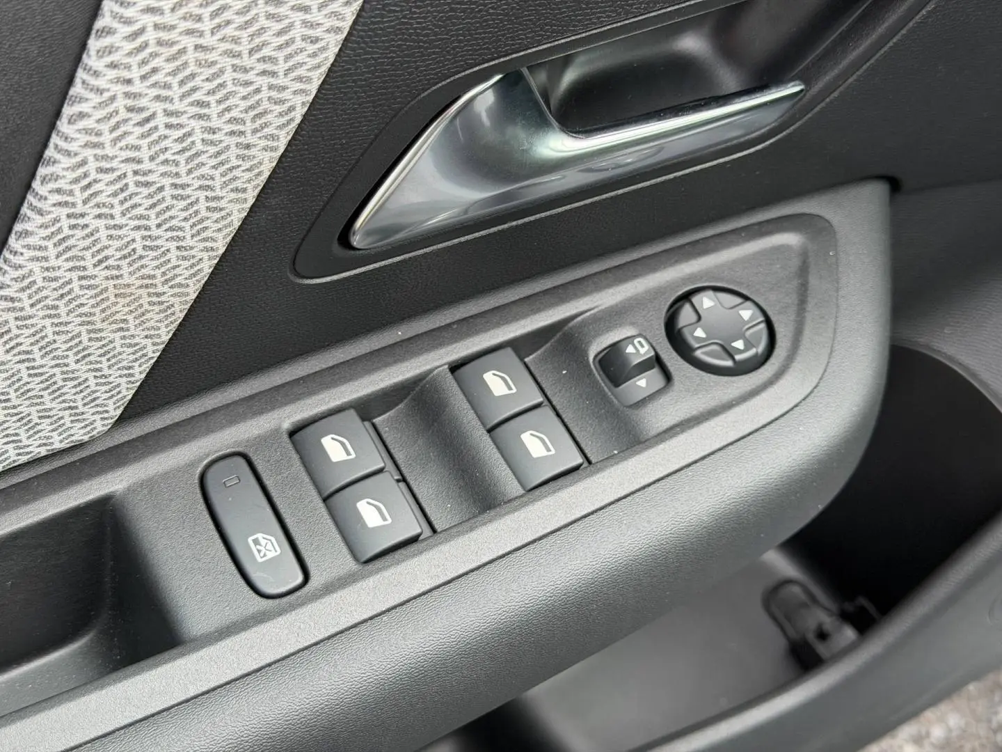 Gros plan sur la commande des vitres et rétroviseurs côté conducteur d'une Citroën C4 électrique blanche 2024.