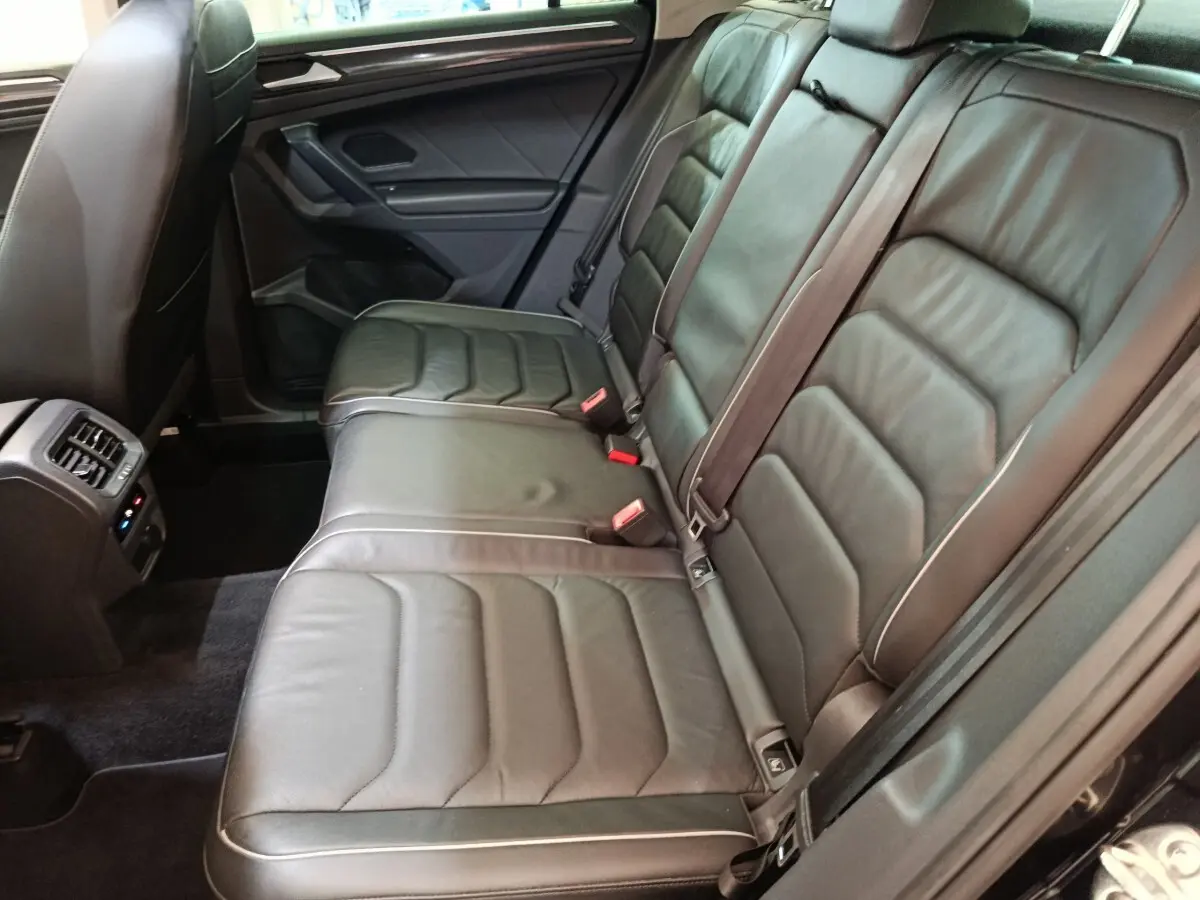 Vue intérieure côté droit des sièges arrière en cuir noir du Volkswagen Tiguan 2.0 TDI 150 DSG7 Elegance 2021 avec ventilation et commandes visibles.