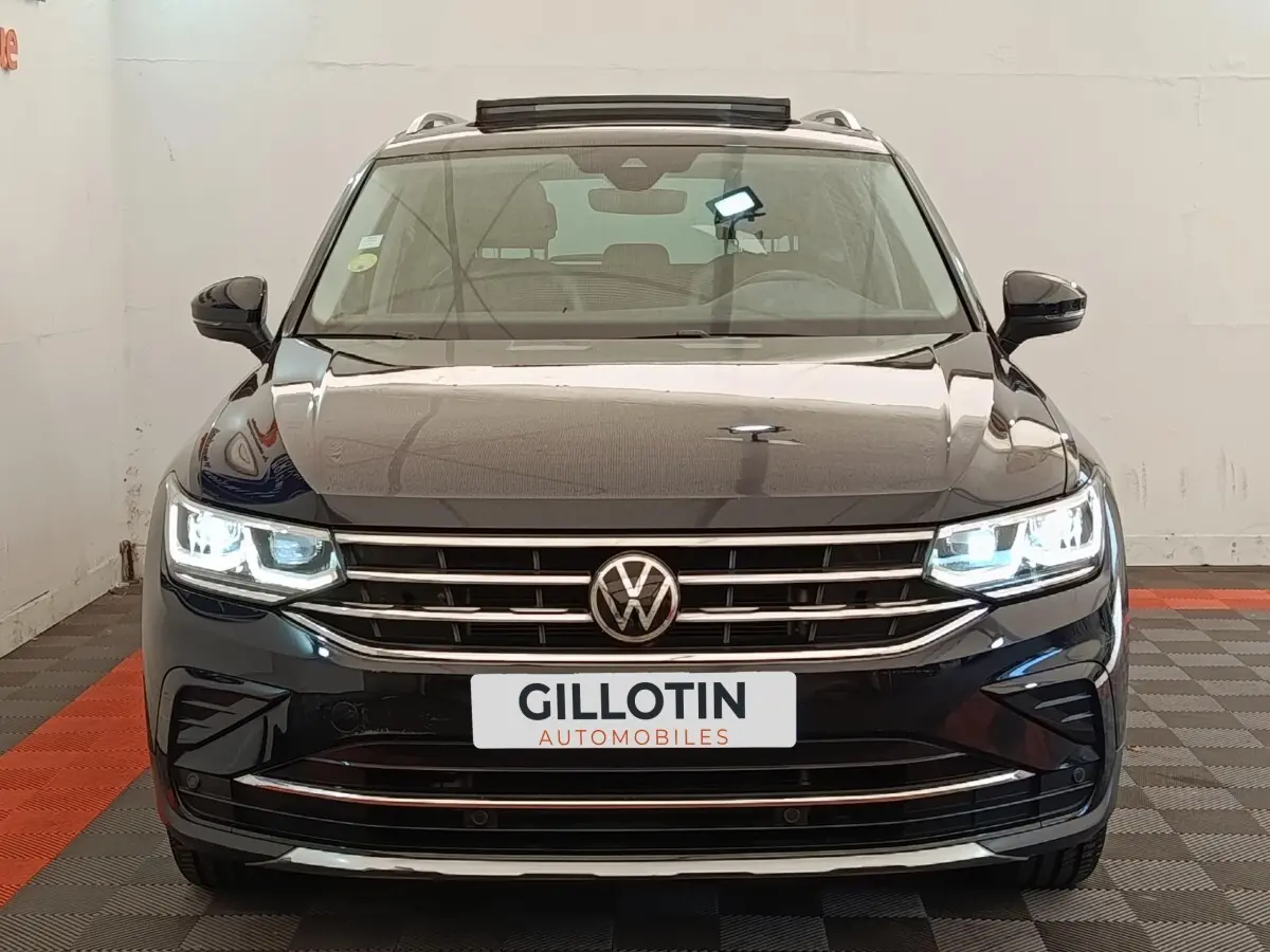 Volkswagen Tiguan noir 2021 vue de face avec phares LED allumés et calandre chromée visible.