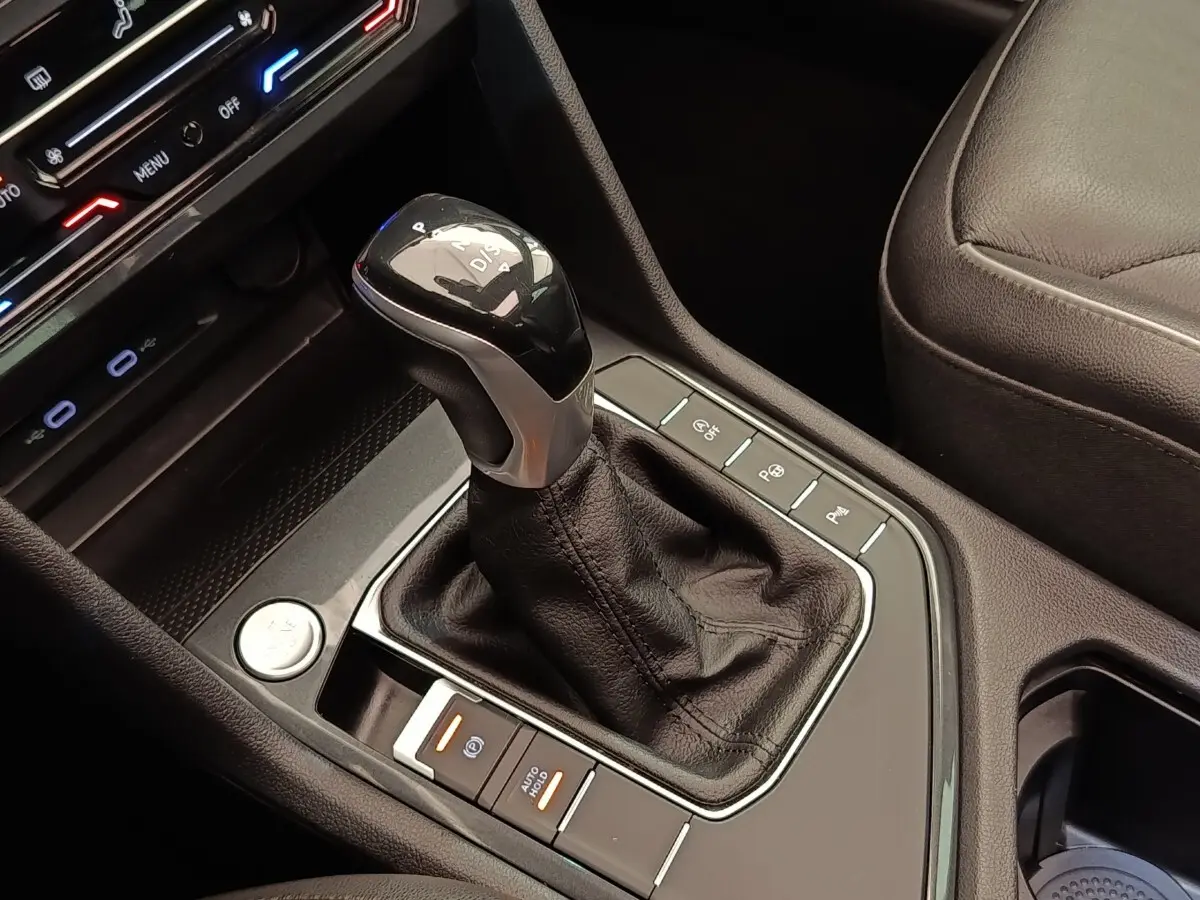 Gros plan sur la console centrale noire du Volkswagen Tiguan 2.0 TDI 150 DSG7 avec levier de vitesse automatique et boutons de contrôle.