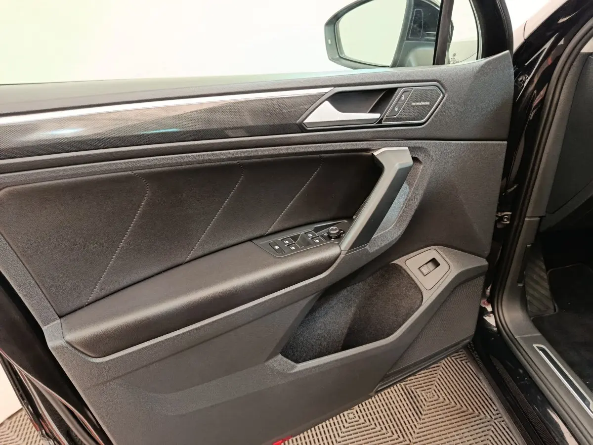 Vue intérieure de la porte avant gauche noire du Volkswagen Tiguan 2.0 TDI 150 DSG7 Elegance avec commandes et insert Harman Kardon.