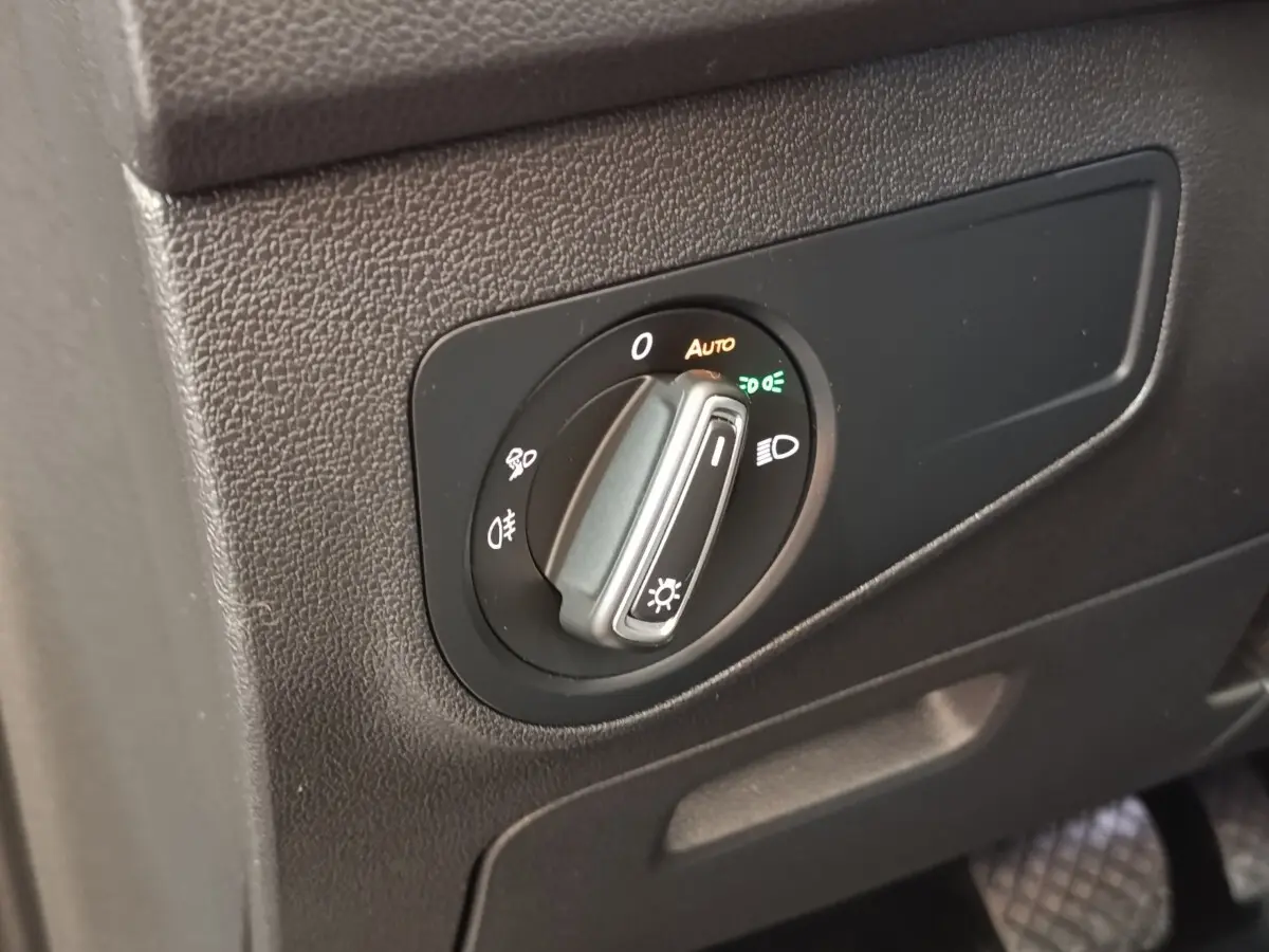 Gros plan sur la commande des phares noire à molette du Volkswagen Tiguan 2.0 TDI 150 DSG7 Elegance, intérieur gris.