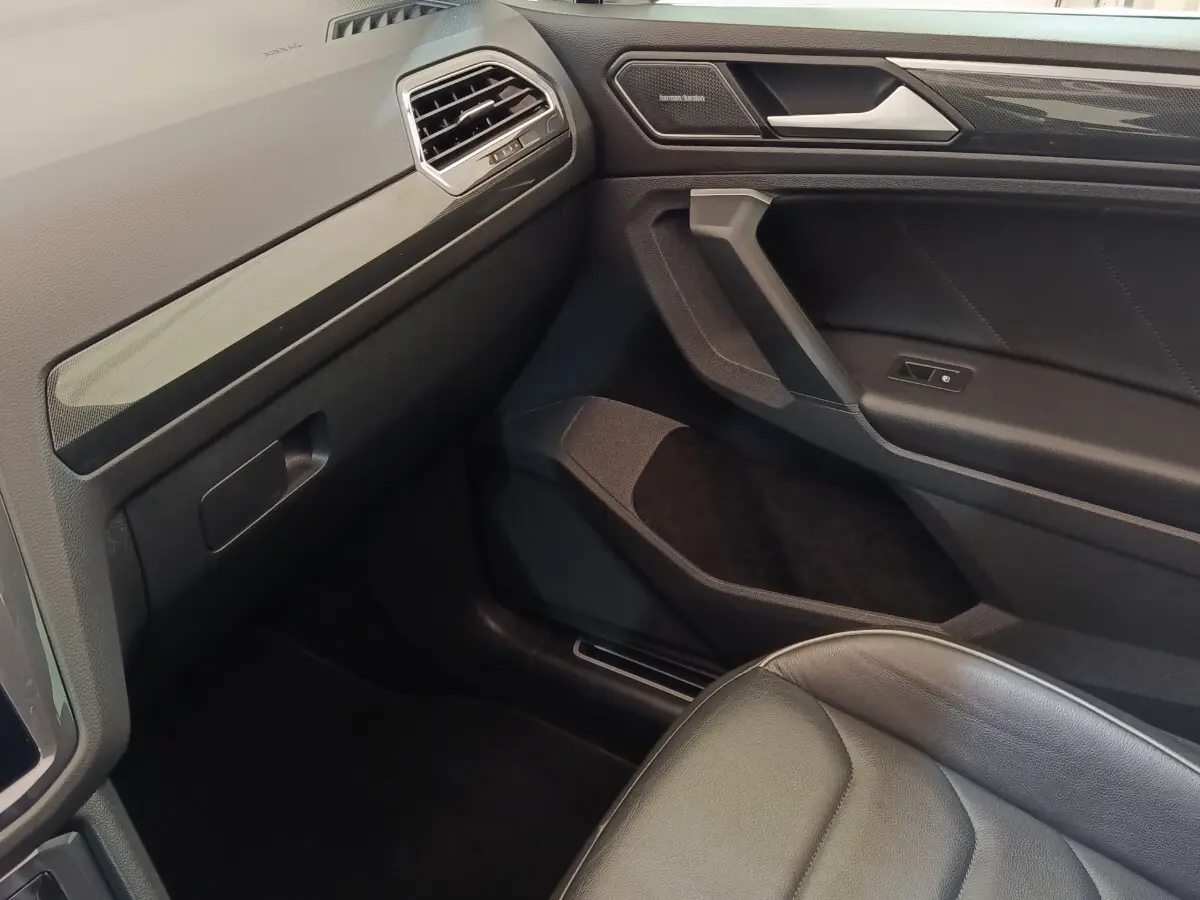 Intérieur côté passager du Volkswagen Tiguan noir 2021, avec siège cuir et garnitures modernes sur la portière.