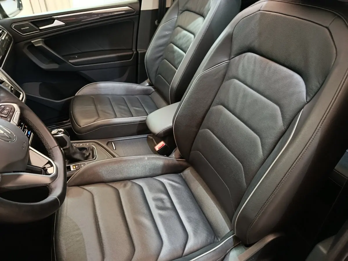 Vue intérieure côté conducteur du Volkswagen Tiguan 2.0 TDI 150 DSG7 Elegance noir avec sièges cuir et volant multifonctions.