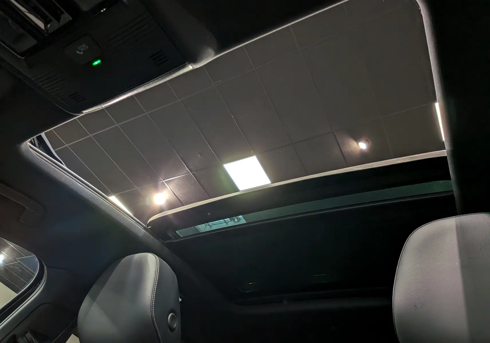 Vue intérieure du toit ouvrant panoramique du Volkswagen T-Roc eTSI 150 CH DSG7 R-Line noir Ébène, avec sièges avant en cuir noir visibles.