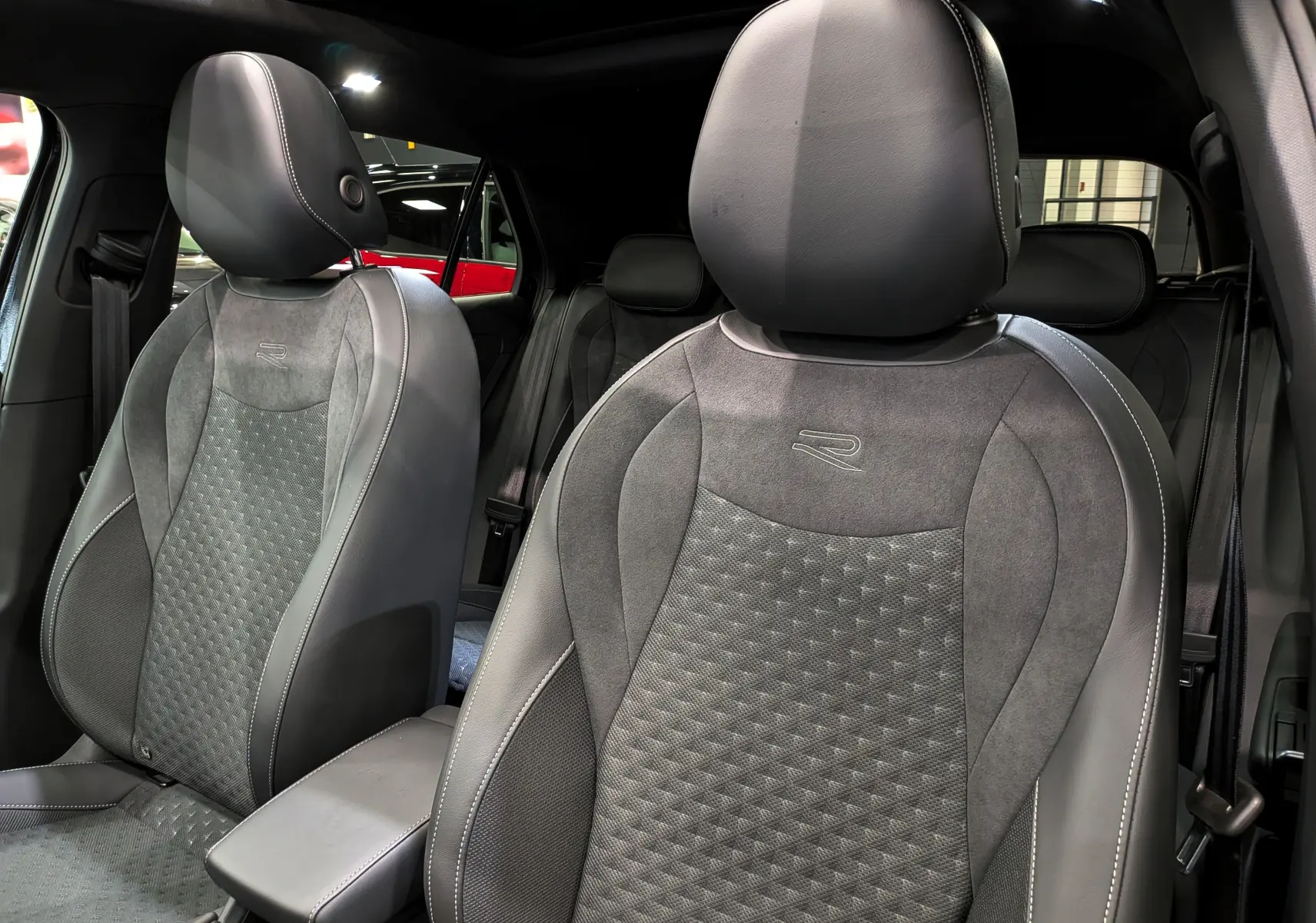 Vue intérieure rapprochée des sièges avant en cuir noir et alcantara avec logo R du Volkswagen T-Roc eTSI 2026.