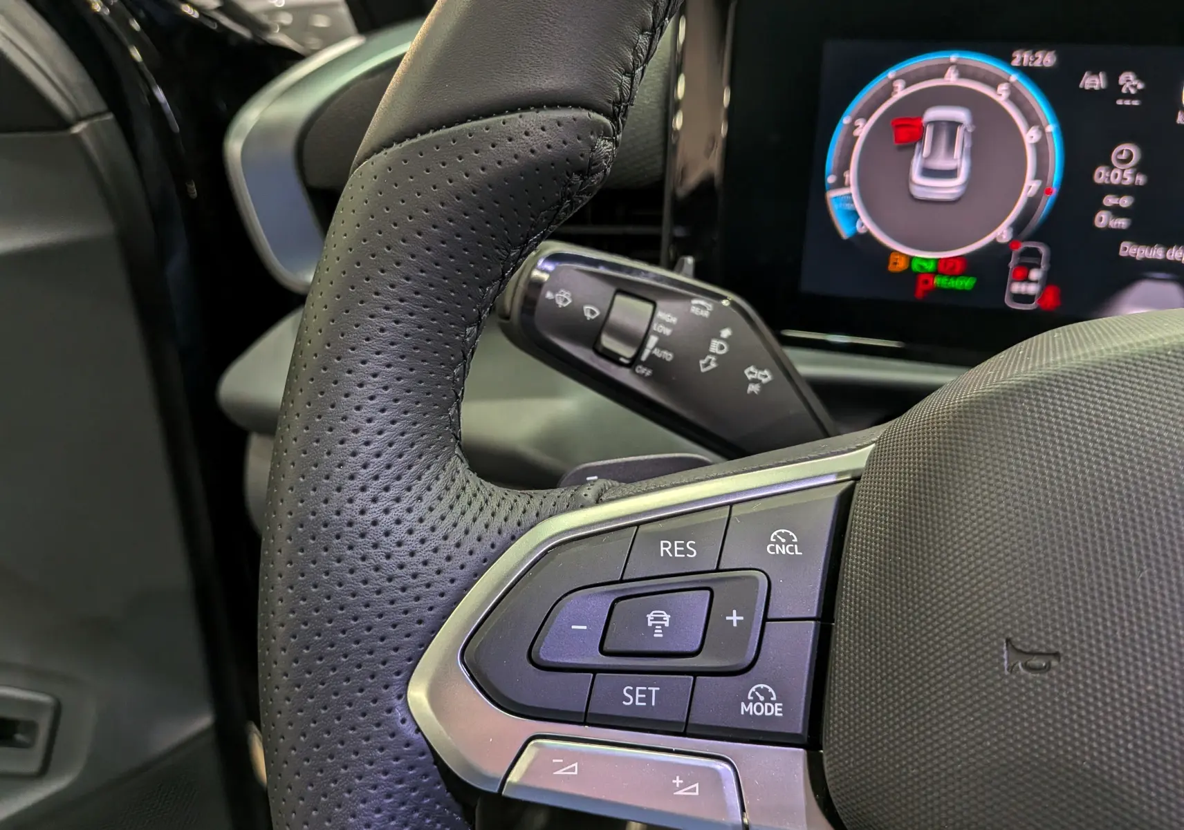 Gros plan sur le volant noir perforé du Volkswagen T-Roc eTSI 150 R-Line 2026 avec commandes de régulateur et tableau de bord numérique.