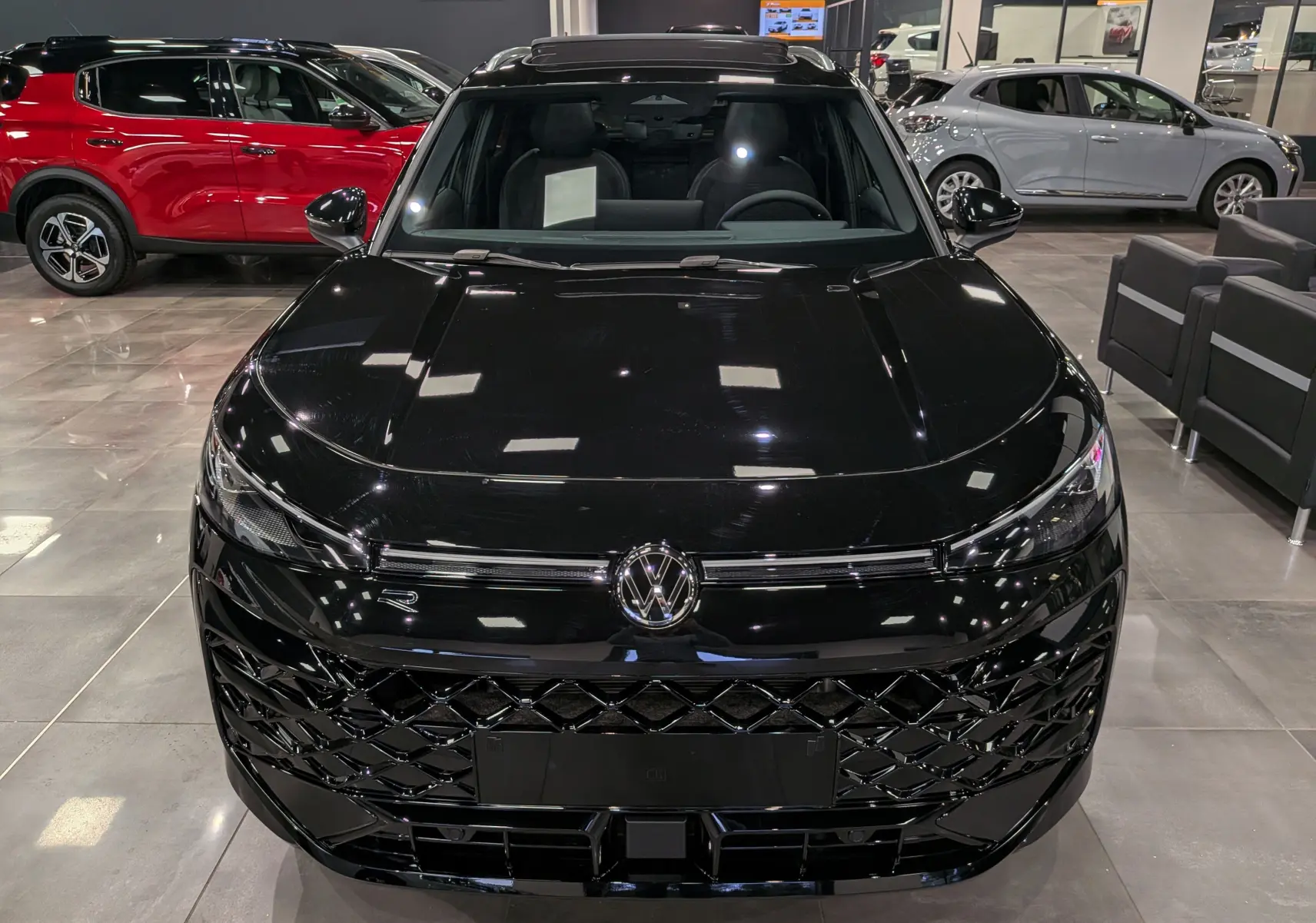 Vue avant d’un Volkswagen T-Roc eTSI 150 CH DSG7 R-Line noir ébène, avec calandre et logo VW bien visibles en showroom.