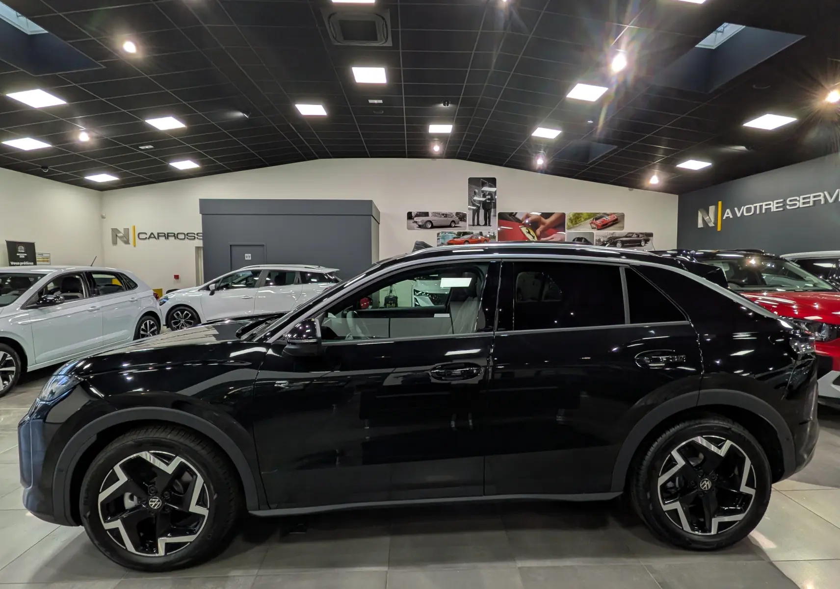 Profil côté gauche du Volkswagen T-Roc eTSI 150 CH DSG7 R-Line noir Ébène avec jantes 18 pouces bicolores en showroom.