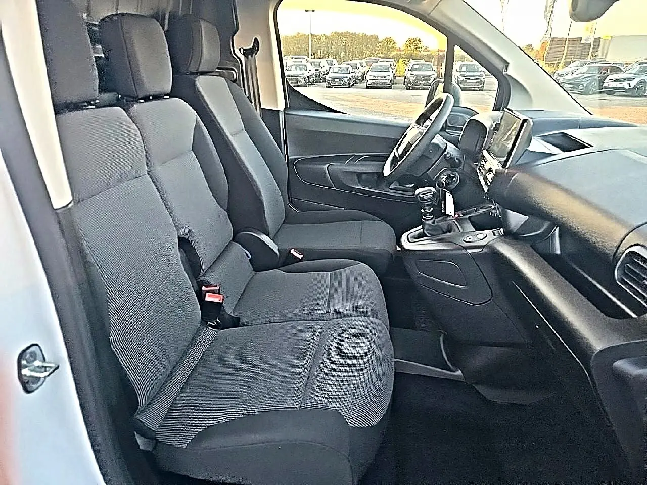 Vue intérieure côté conducteur du Citroën Berlingo Fourgon blanc, montrant les sièges avant et le tableau de bord avec boîte manuelle.