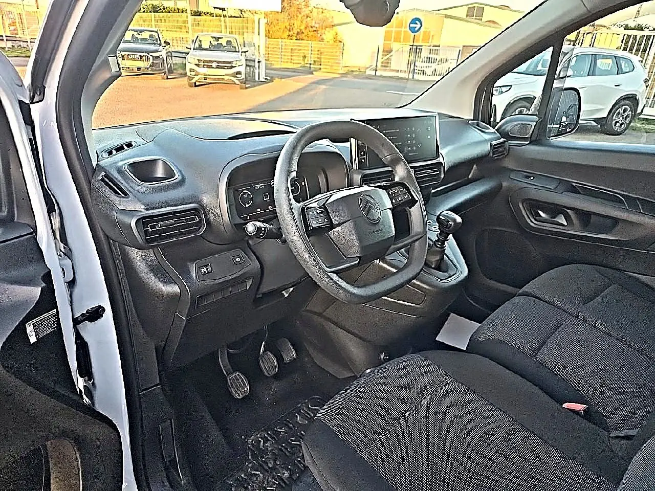 Vue intérieure côté conducteur du Citroën Berlingo Fourgon blanc, volant multifonction et tableau de bord moderne visibles.